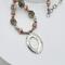 Handcrafted necklace with Rhodochrosite and Labradorite beads, silver accents, and an embossed pewter pendant on a 20-inch strand.